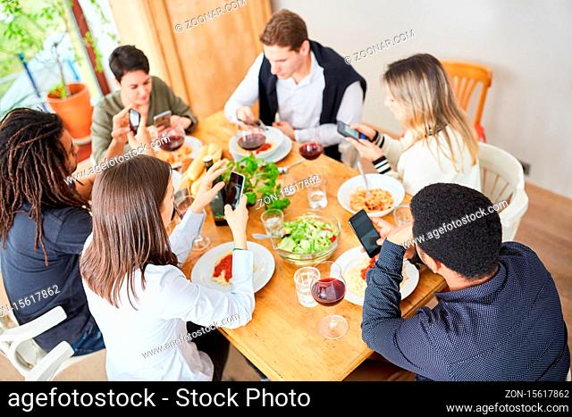 Unhöfliche Freunde schauen alle auf ihr Smartphone beim gemeinsamen Mittagessen am Tisch