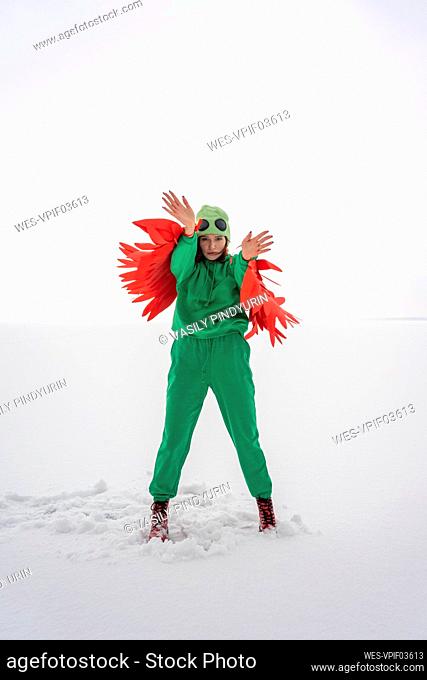 Young woman in bird costume showing stop gesture against sky