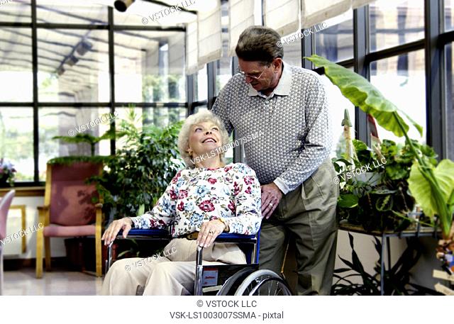 Man helping woman in wheelchair