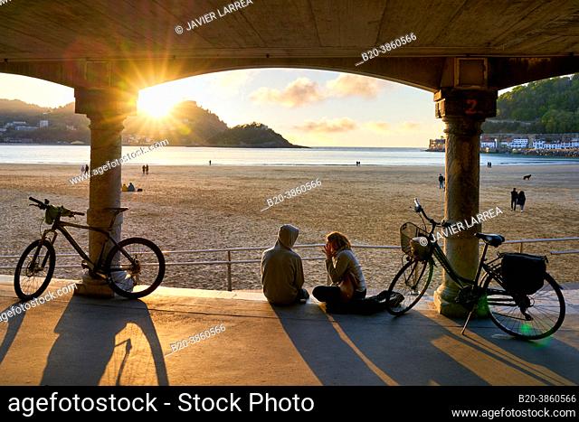Couple with their bicycles, Sunset on La Concha Beach, Donostiarra jewel par excellence, emblem of the city, incomparable setting