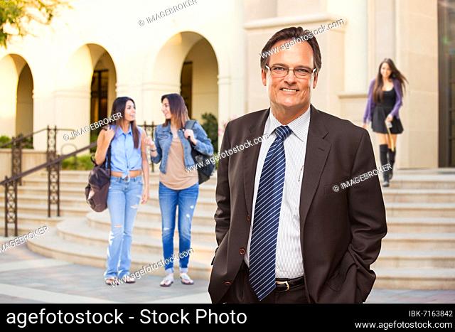 Male adult administrator in suit and tie walking on campus