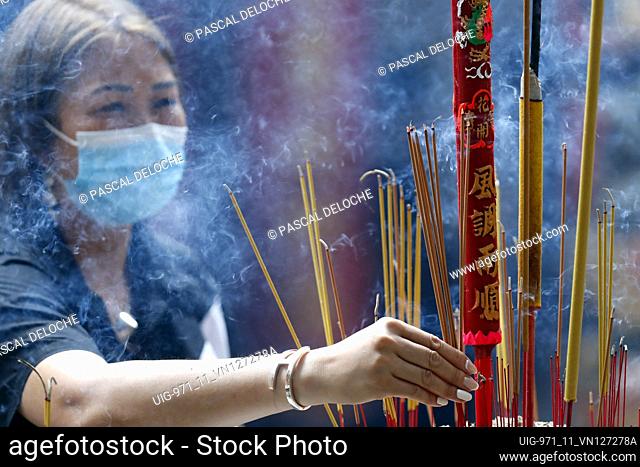 Ba Thien Hau Chinese Temple. Buddhist woman praying with incense sticks. Faith concept. Woman praying with incense sticks in her hand