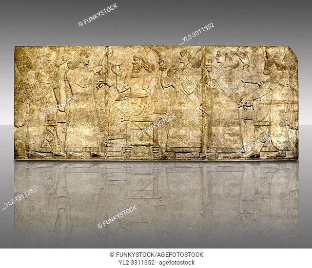 Assyrian relief sculpture panel of King Ashurnaspiral II enthroned between two attendants. The group is flanked by winged protective spirits