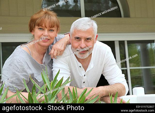 Portrait of senior couple standing in front of their home