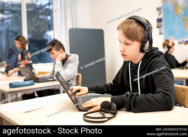 Boy in classroom using laptop