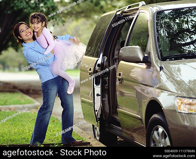 Mother picking her daughter up out of the car