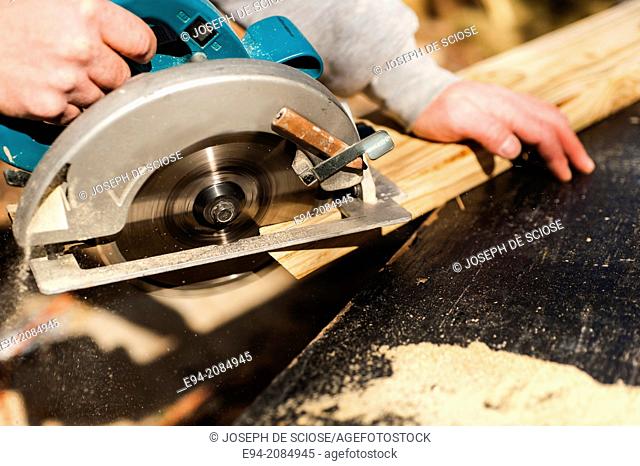 A man cuts a piece of lumber with a circular power saw