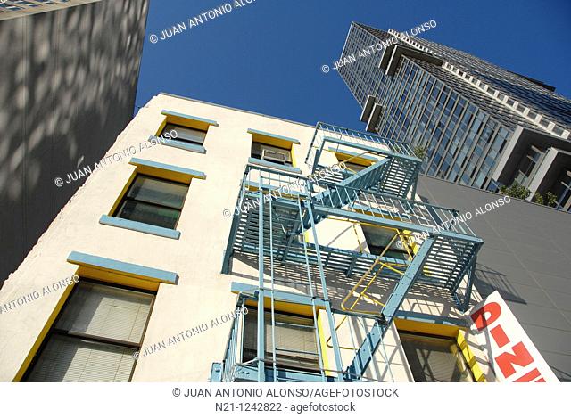 Low building with fire escapes between high rise apartment buildings on 42nd Street near The Hudson River. Theater District. Manhattan