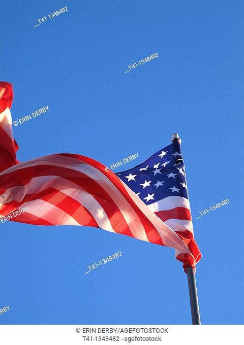 The American Flag blowing in the wind against a blue sky