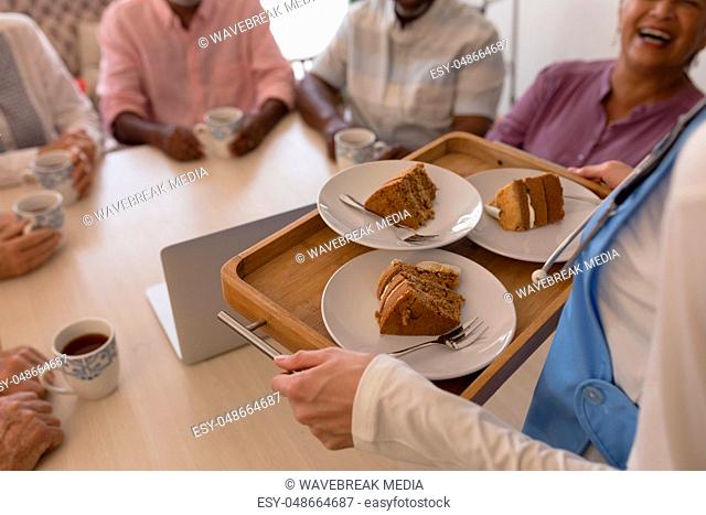 Female doctor holding tray of cake at home