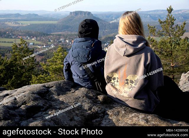 Two children sitting on the Papststein, behind them the Lilienstein, table mountain in the Elbsandsteingebirge, located at the Malerweg, Papstdorf, Saxony