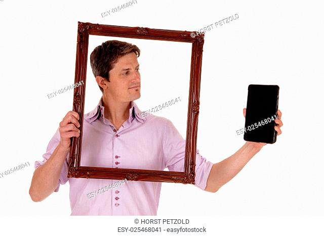 A young man holding up a picture frame, looking trough on his tablet, .isolated for white background.