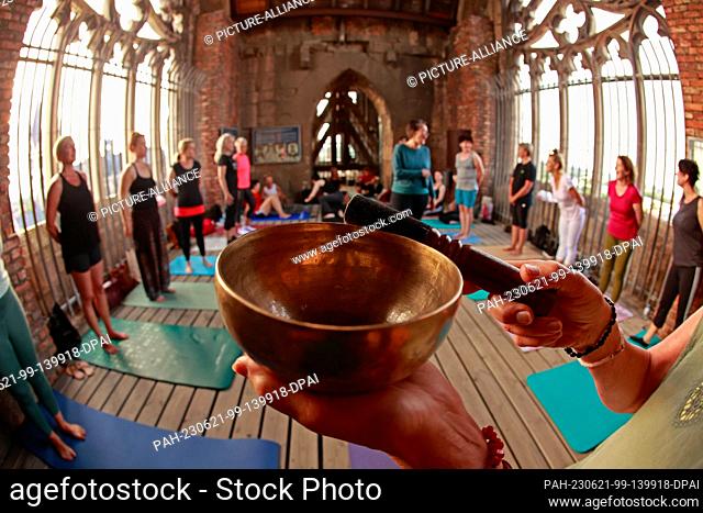 21 June 2023, Saxony-Anhalt, Halberstadt: The yoga session on the towers of the Martini Church in Halberstadt opens with a singing bowl