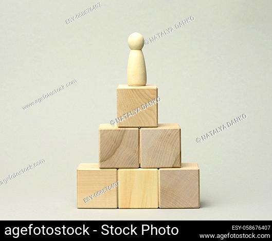 wooden figurine of a man at the top of the pyramid. The concept of career growth, goal achievement. Personal growth, head of corporation, CEO