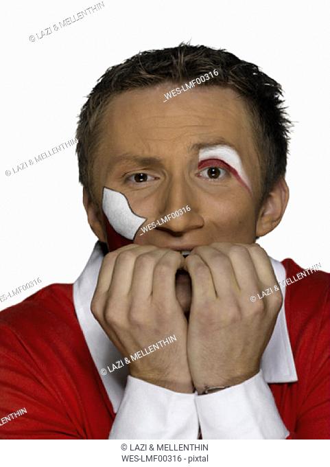 Young man with Poland flag painted on face biting fingernails, close-up