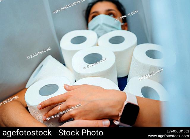 People are stocking up toilet paper for home quarantine from coronavirus. Woman holds many rolls of toilet paper