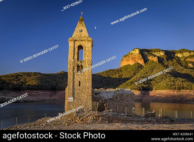 Bell tower of Sant RomÃ  de Sau at sunrise with the Sau reservoir almost empty during the 2022-23 drought (Osona, Barcelona, Catalonia, Spain)
