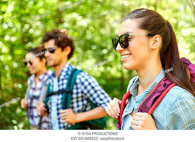 group of friends with backpacks hiking in forest