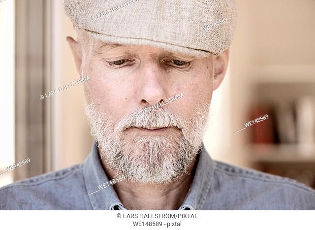 Portrait of old man looking down. Serious and pensive facial expression