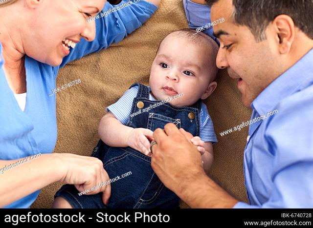 mixed-race family playing face up on the blanket