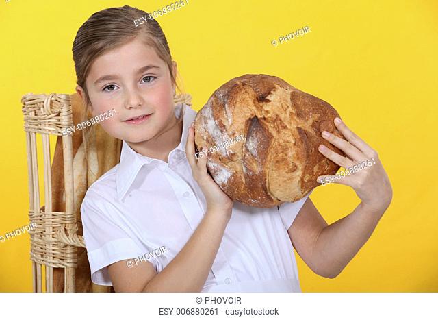 Proud young girl holding up a bread loaf
