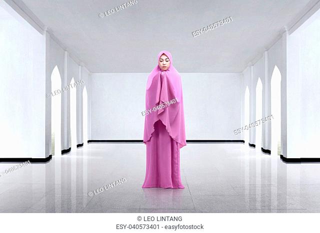 Young asian woman wearing veil and praying on the mosque