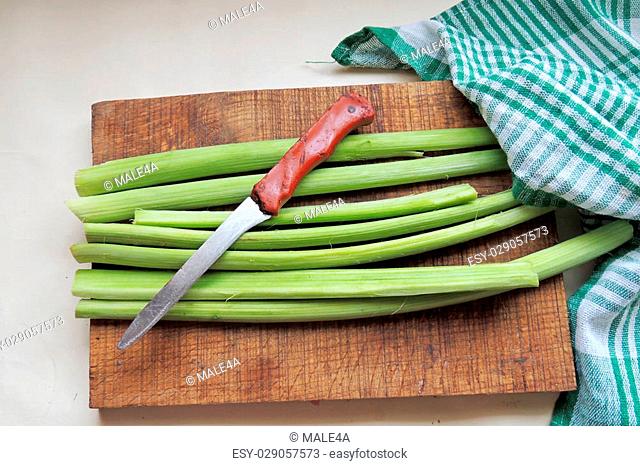 rhubarb stalks with leaves, freshly picked from the garden on a wooden table, closeup with selected focus, narrow depth of field