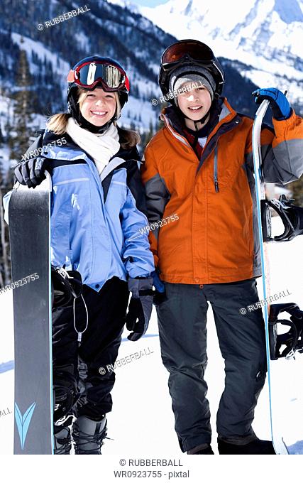 A brother and sister with snowboards outside