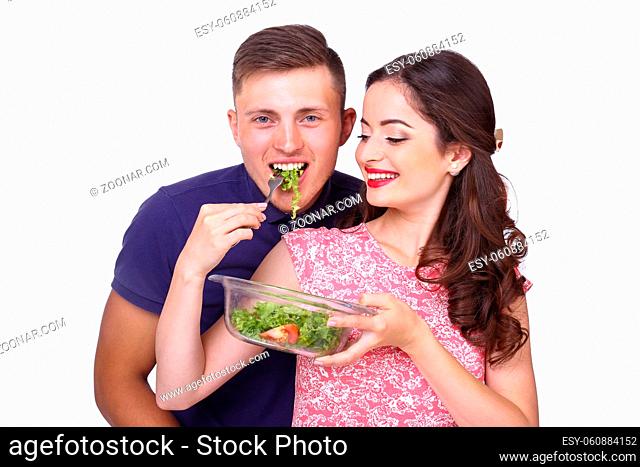 A loving young couple cut vegetables for salad isolated on white background