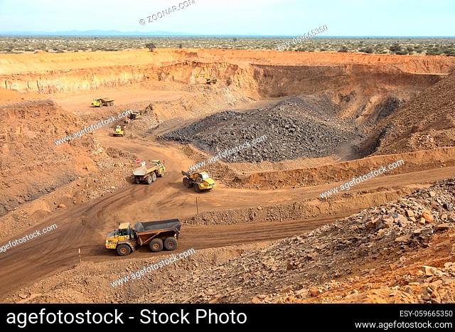 Open pit Manganese Mining - Excavator digging out ore rich rock and loading it onto rock dump trucks for processing