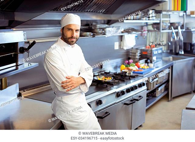 Portrait of smiling chef standing with arms crossed in commercial kitchen