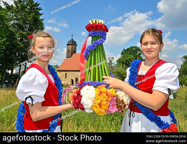 18 June 2023, Brandenburg, Casel: At the beginning of the Johannisreiten, Annelie (l) and Pauline wear a crown of flowers, rushes and water lilies