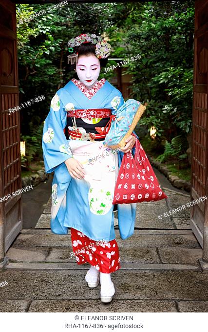 Maiko, apprentice geisha, leaves okiya (geisha house) through garden gate for evening appointment, Gion, Kyoto, Japan, Asia