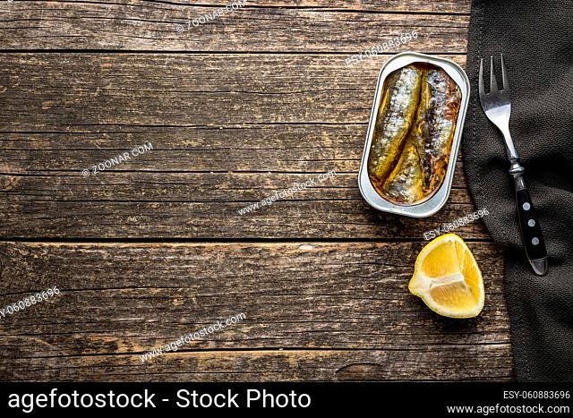 Canned sardines. Sea fish in tin can on wooden table. Top view