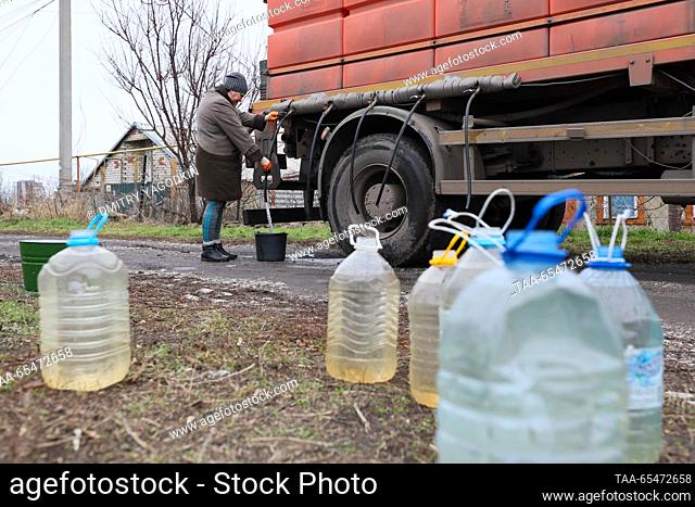 RUSSIA, DONETSK - DECEMBER 4, 2023: A woman fills a bucket with water from a tank truck in Donetsk's Leninsky District. Due to problems with water supply