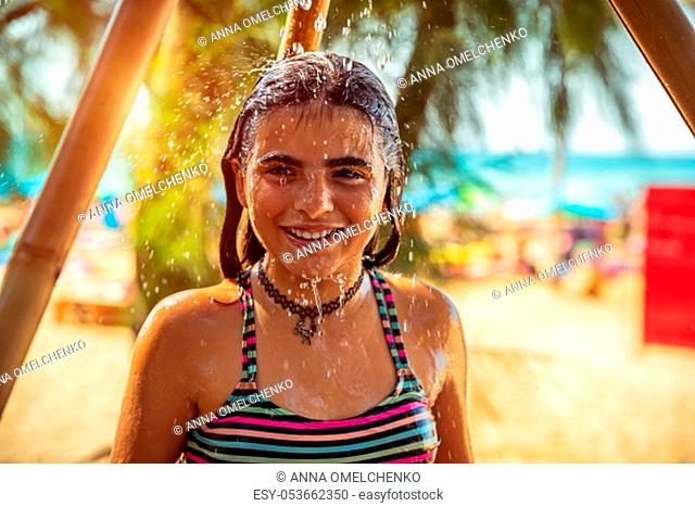 Portrait of a beautiful little girl on the beach resort, happy child taking shower on the beach, having fun outdoors, enjoying summer holidays near the sea