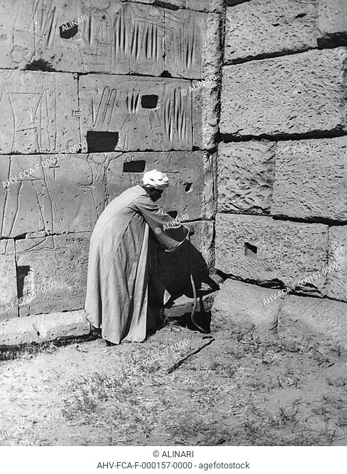 Man portrait near a wall engraved with figures of deities, Egypt, shot 1950-1960 by Clerici Fabrizio