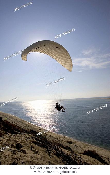 Paraglider silhouetted against evening sun over the Bassin d'Arcachon, . south of Bordeaux, France