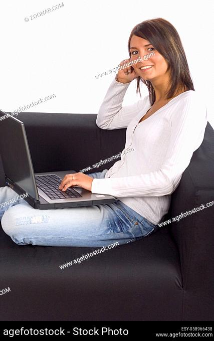 Young woman sitting on the black sofa with laptop. White background, in studio