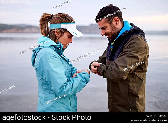 Couple setting smart watch before running at beach