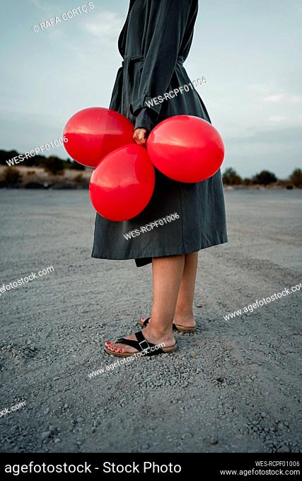 Woman holding balloon while standing at road