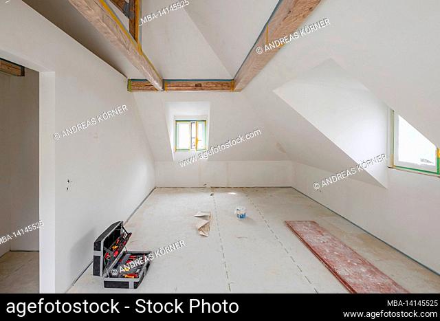construction site, refurbishment and renovation of an apartment, empty room in the attic with wooden beam ceiling and dormer