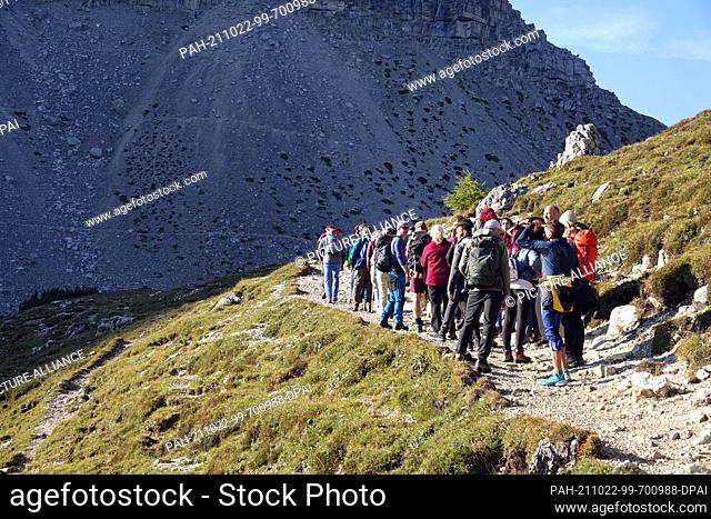 05 October 2021, Italy, Sexten: A group of hikers on a path near the Three Peaks (Italian: Tre Cime di Lavaredo) in the Sesto Dolomites