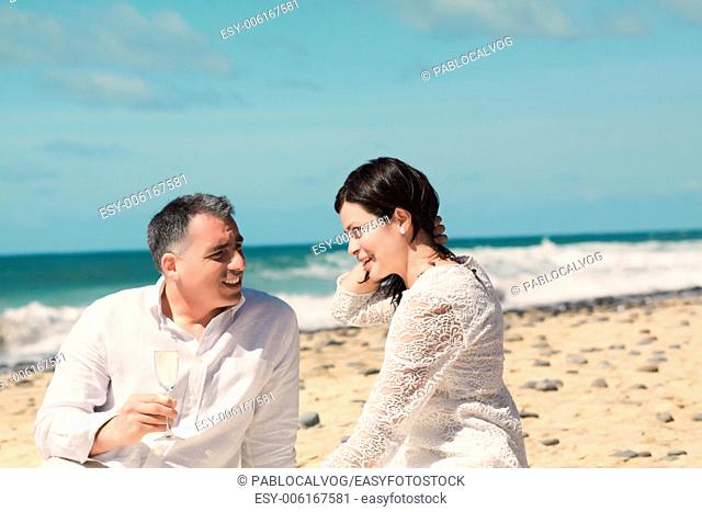 couples talking and sitting on the beach with champagne