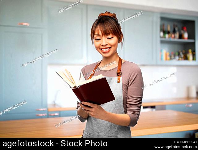 smiling woman in apron reading cook book