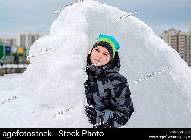 Teen boy standing in a makeshift snow fort