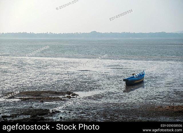 An old abandoned rowboat in shallow water, Goa, India