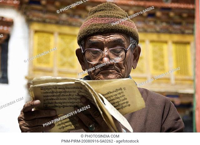 Senior man reading Buddhist scriptures in a monastery, Likir Monastery, Ladakh, Jammu and Kashmir, India