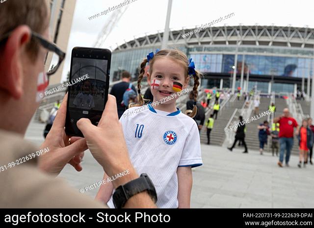 31 July 2022, Great Britain, London: Soccer, Women, European Championship 2022, England - Germany, Final, Wembley Stadium: A father takes a photo of his...