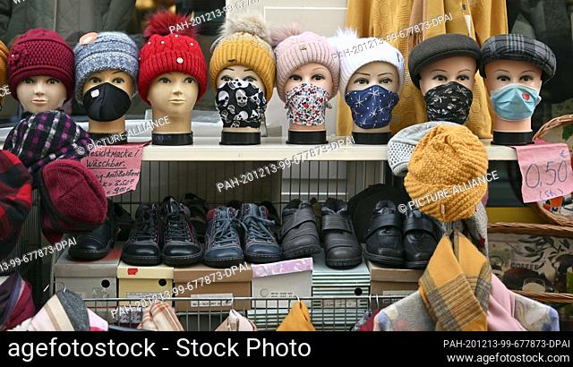08 December 2020, Thuringia, Mühlhausen: Mannequin heads with face masks, scarves and caps are standing in front of a clothing store in the old town